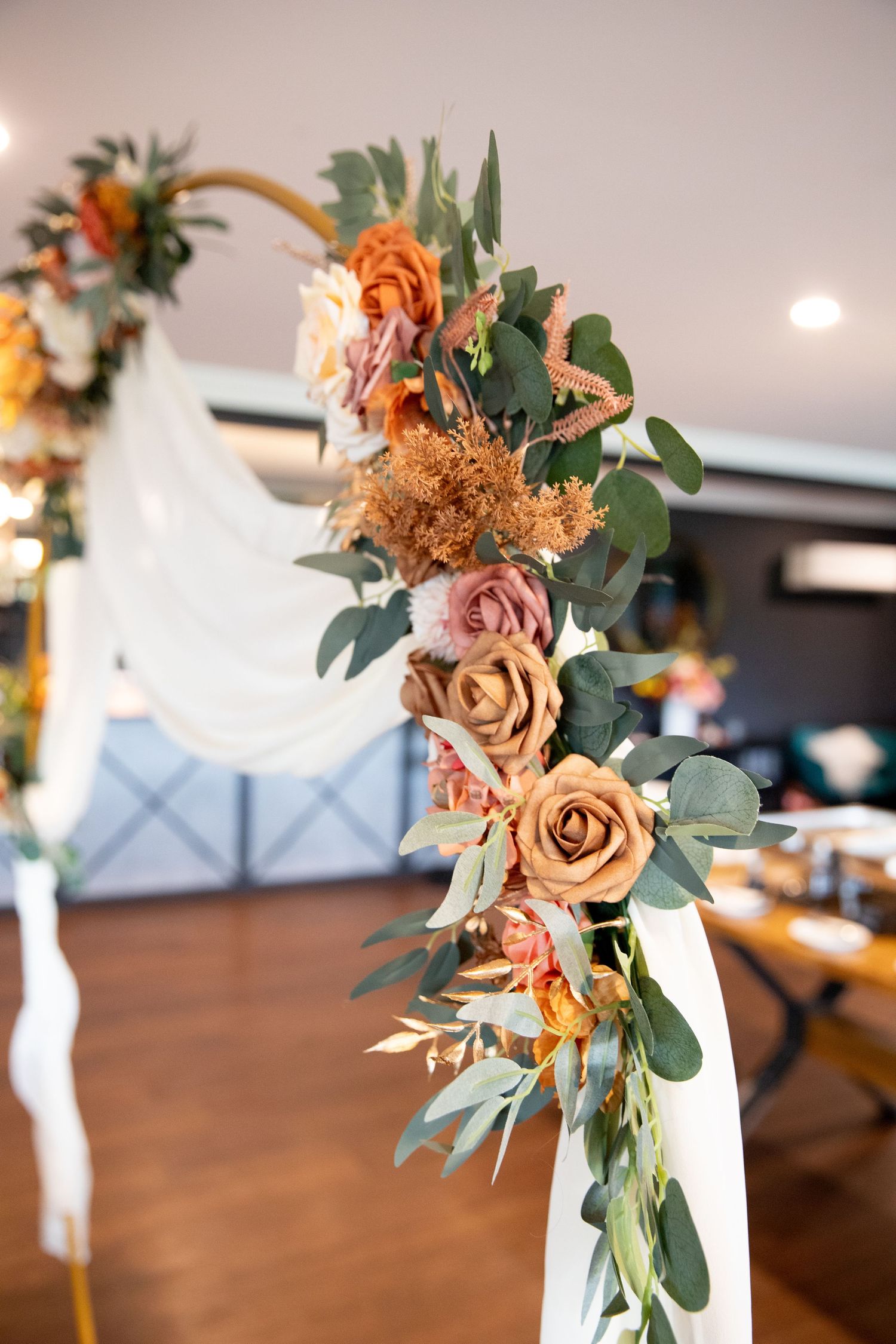 Elegant floral arrangements with peach roses and eucalyptus leaves on wooden tables.
