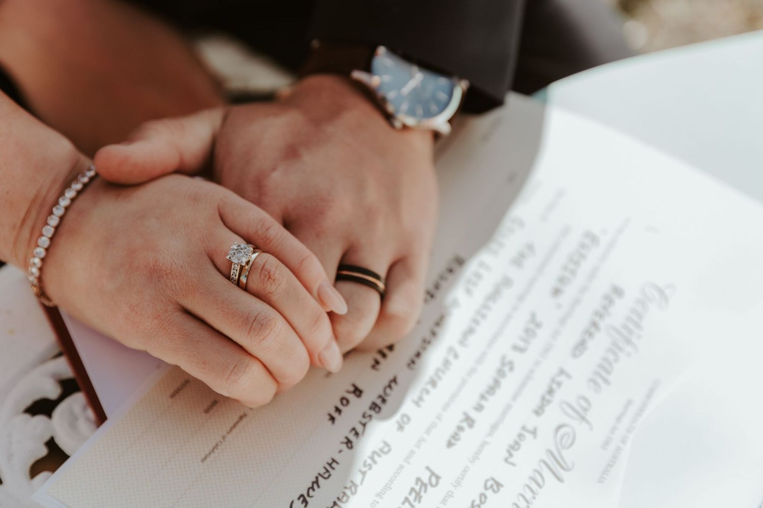 Close-up of hands signing wedding documents on white paper.