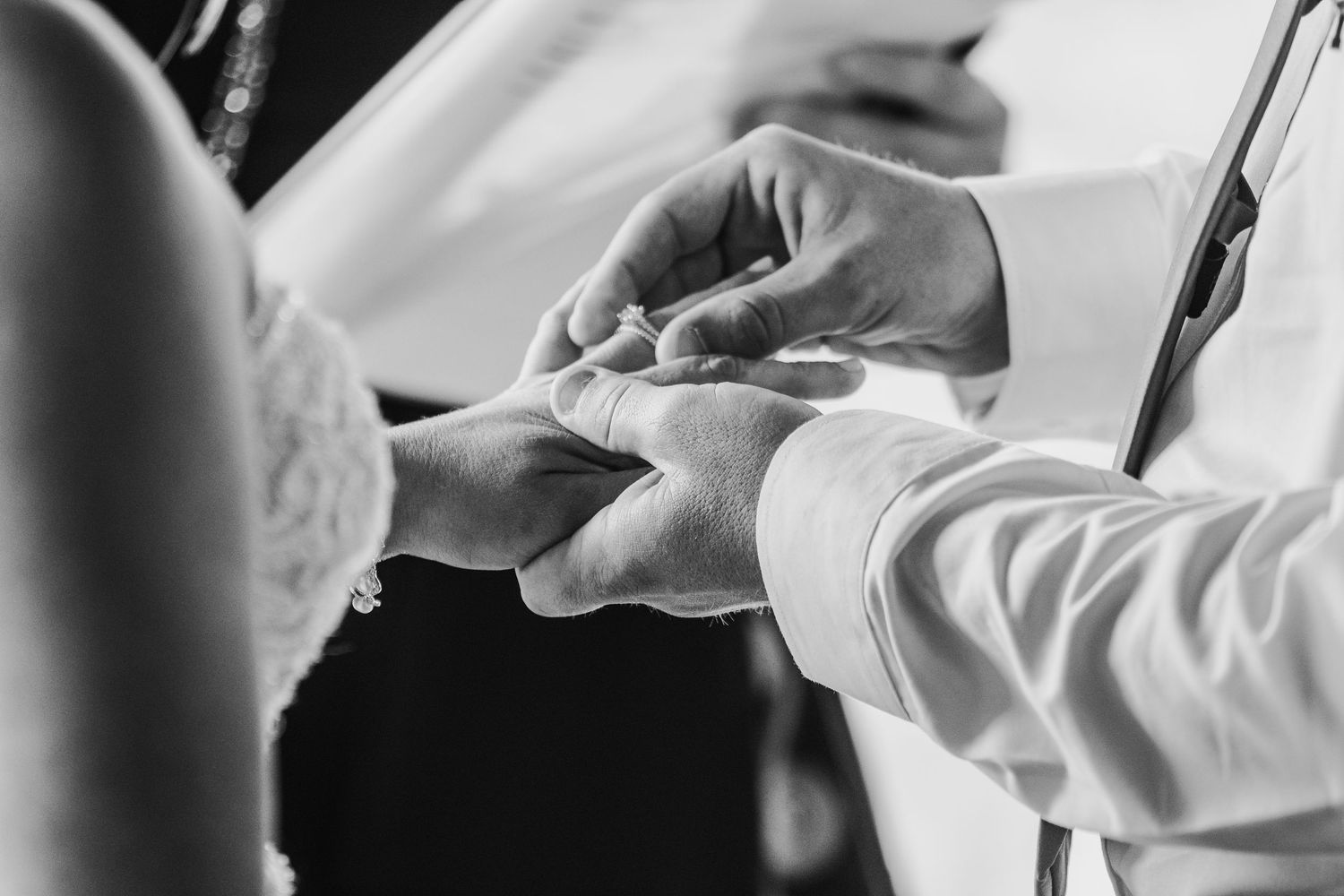 Black and white detail shot of formal wedding attire and hands.
