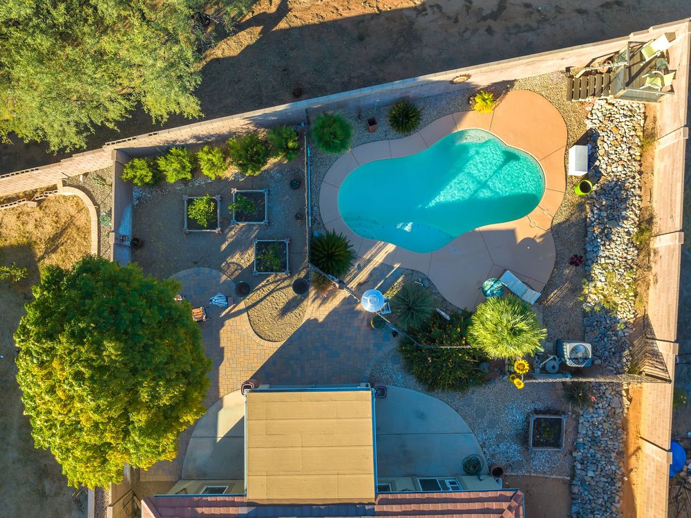 Aerial view of backyard swimming pools and patios in residential neighborhood during sunny day.