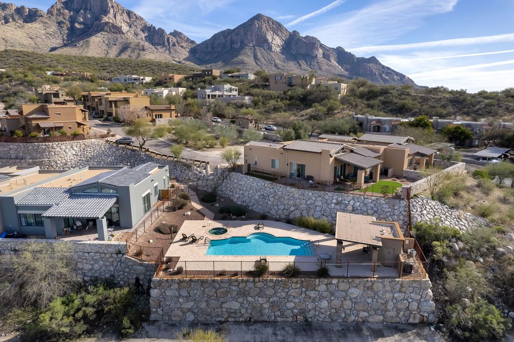 Modern desert home with infinity pool nestled against rugged mountain backdrop in scenic southwestern landscape.