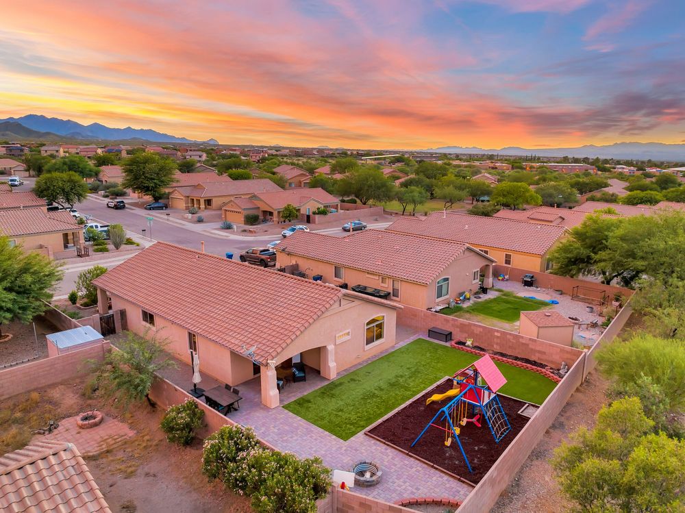 Aerial drone panorama of desert homes with terracotta roofs at sunset showing vibrant orange and pink sky.