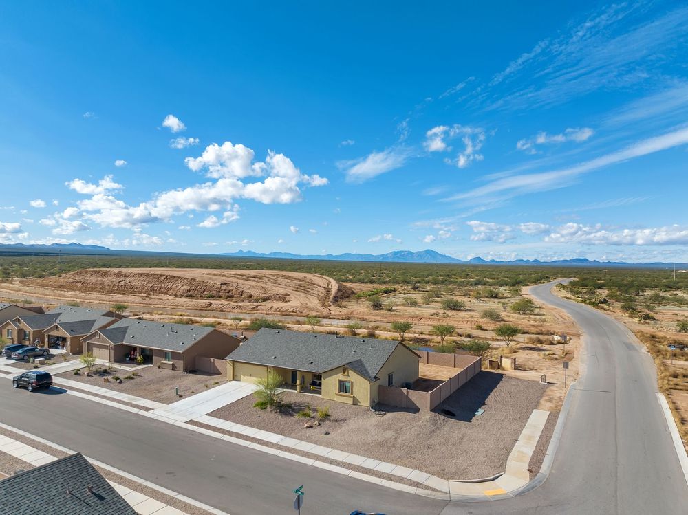 Aerial panoramic view of a new residential development in a desert landscape with winding roads and scattered homes.