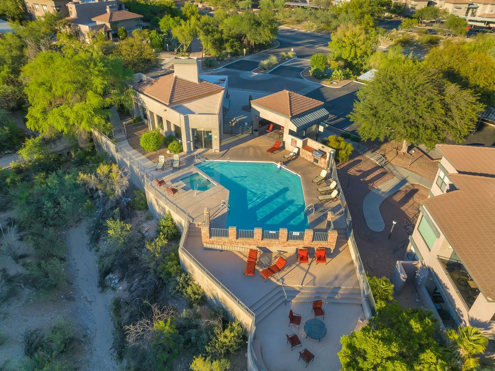 Aerial view of luxury resort with multiple swimming pools and palm trees surrounded by Mediterranean-style buildings.