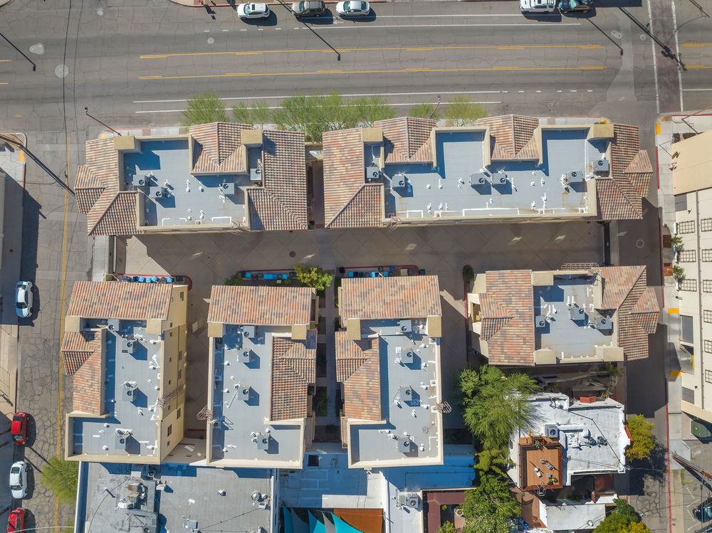 Aerial view of suburban neighborhood with residential houses, swimming pools, and parked cars on streets.