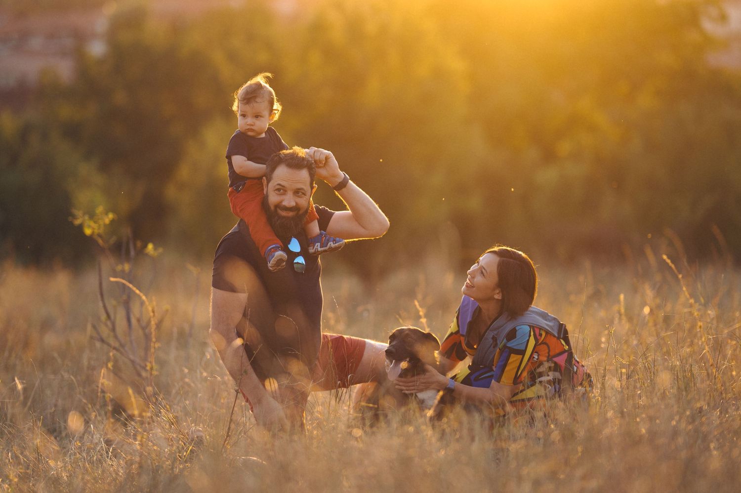 Silhouetted figures sitting together in a sunlit meadow during golden hour creating a dreamy outdoor scene.