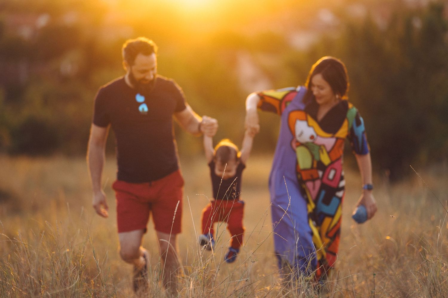 Group playing sports in a grassy field during golden hour sunset with sun flare in background.
