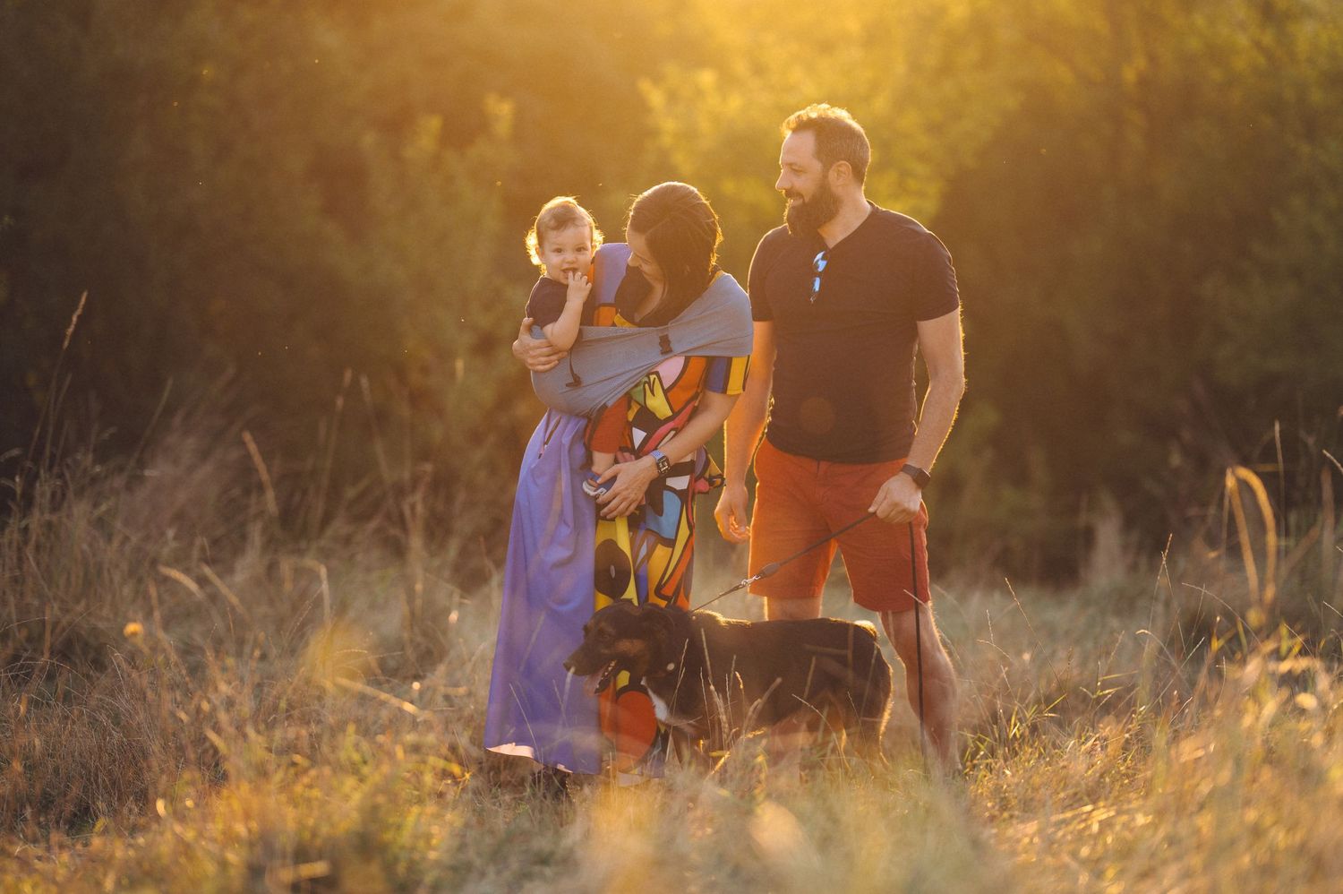Group of people walking together on a dirt path during golden hour sunset in a misty meadow.