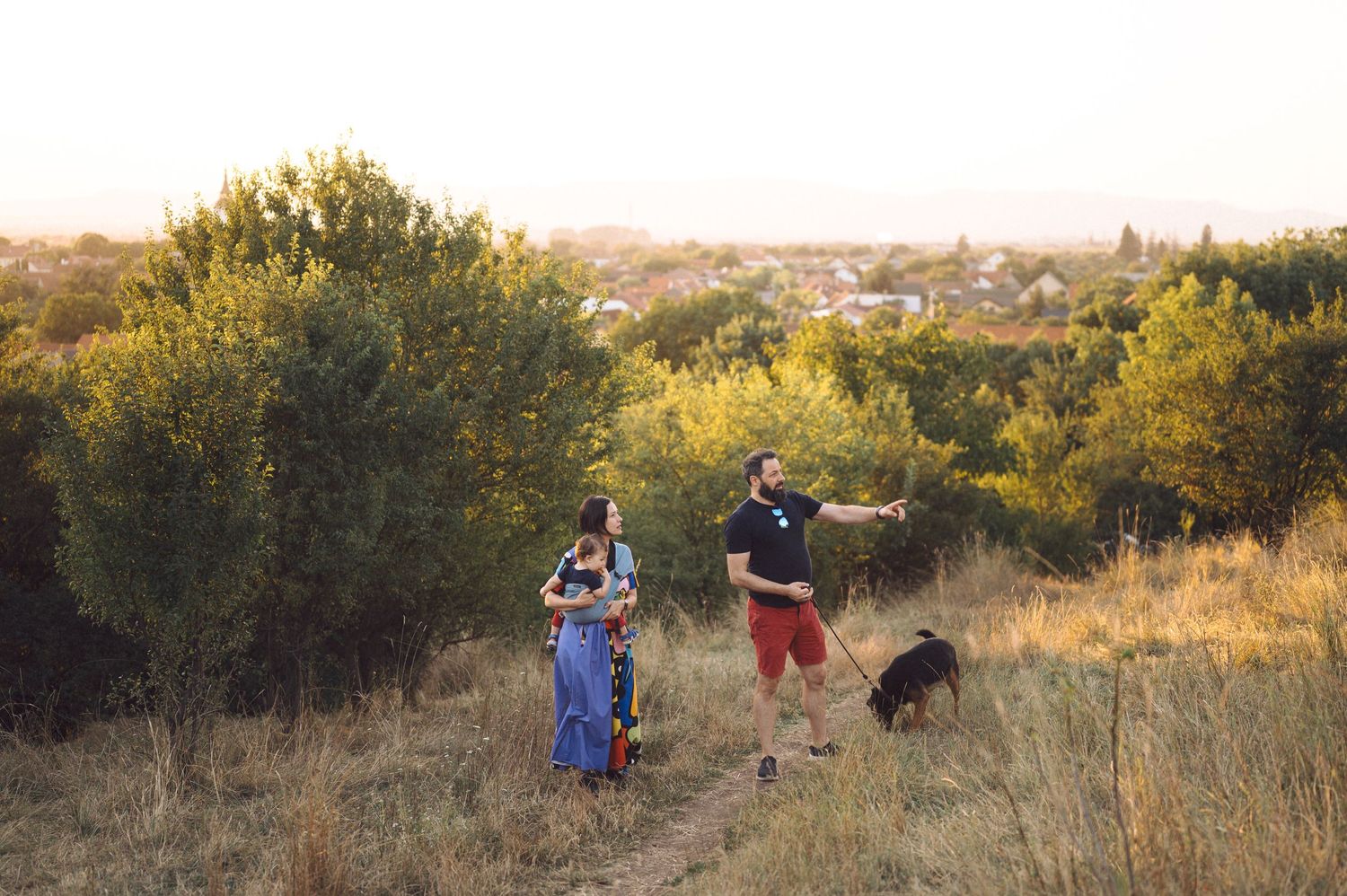 A group of people gathered in a golden field during sunset taking professional photographs.