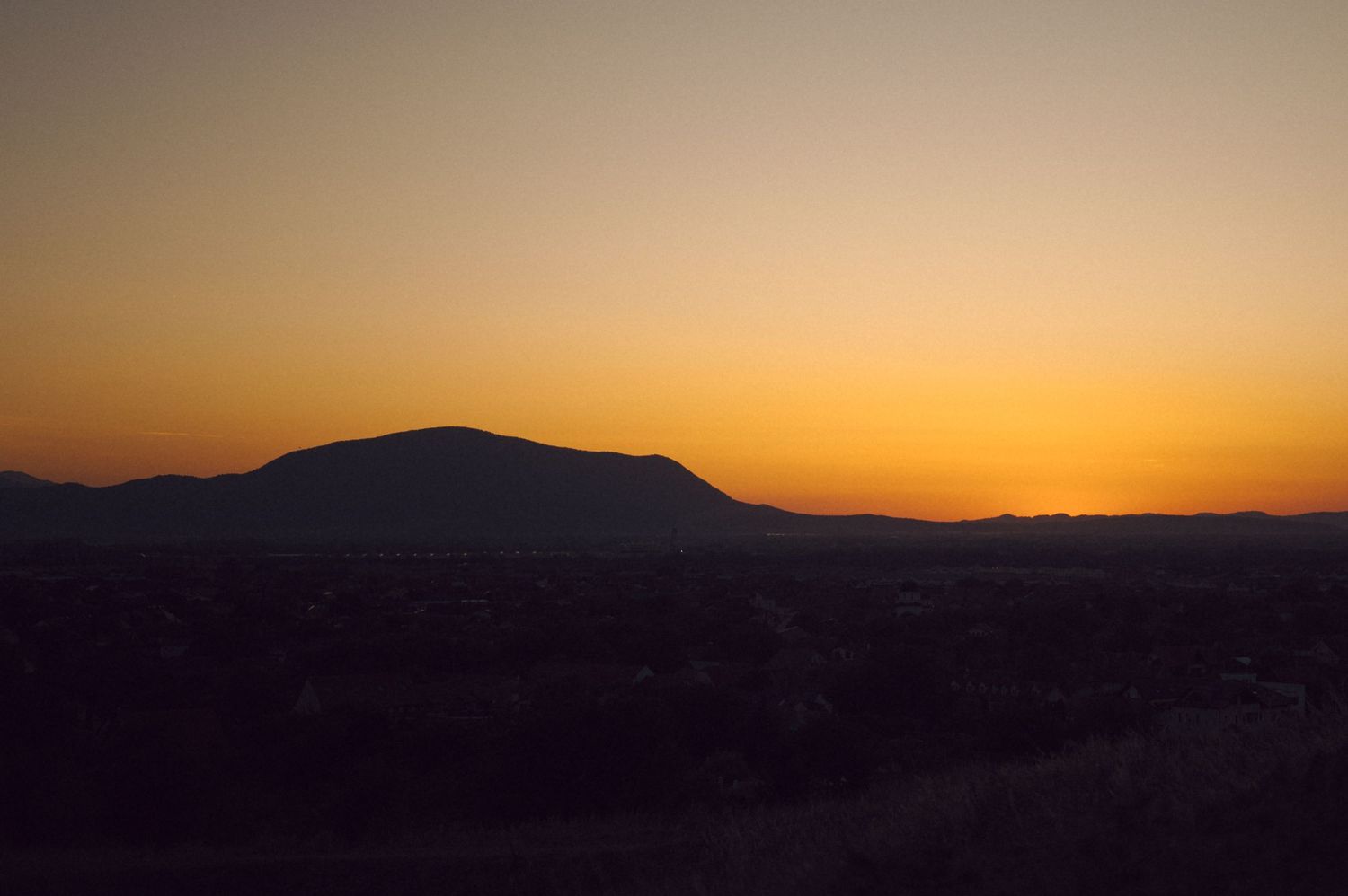 A colorful desert sunrise silhouettes distant mountain ranges against a vibrant orange and pink sky.