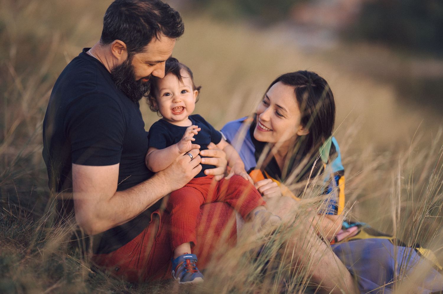 Family enjoying a picnic together outdoors in a golden field during sunset.