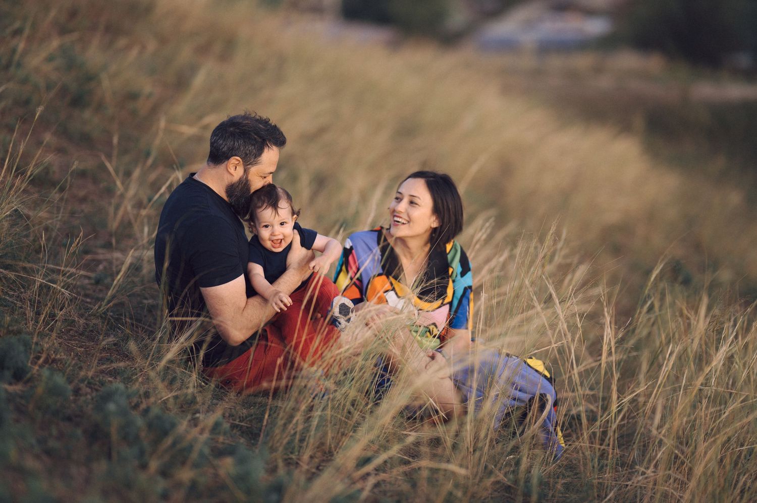 A series of romantic candid moments between a couple sitting in tall grass during golden hour sunset.