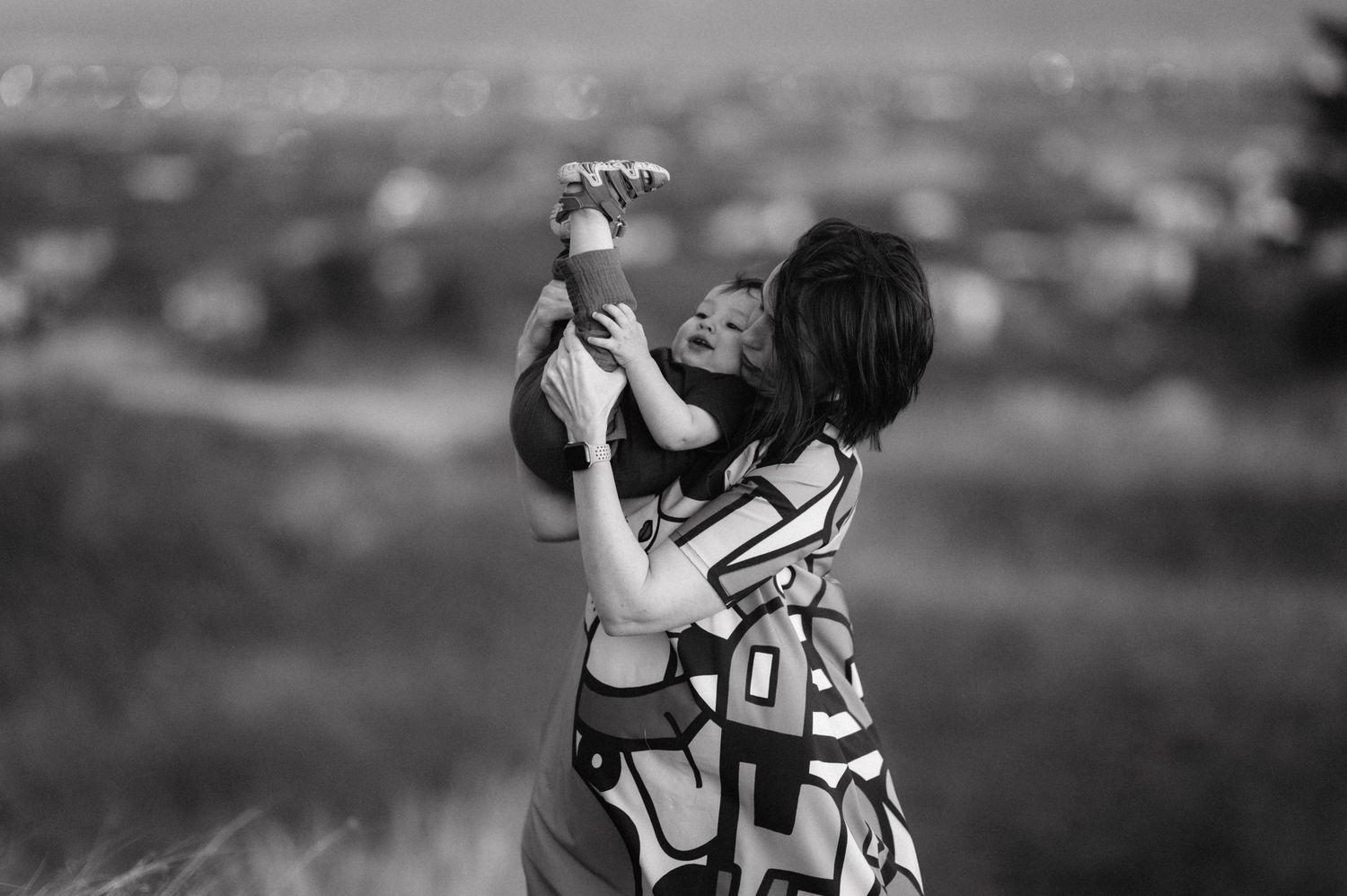 A tender moment captured in black and white against a cityscape backdrop.