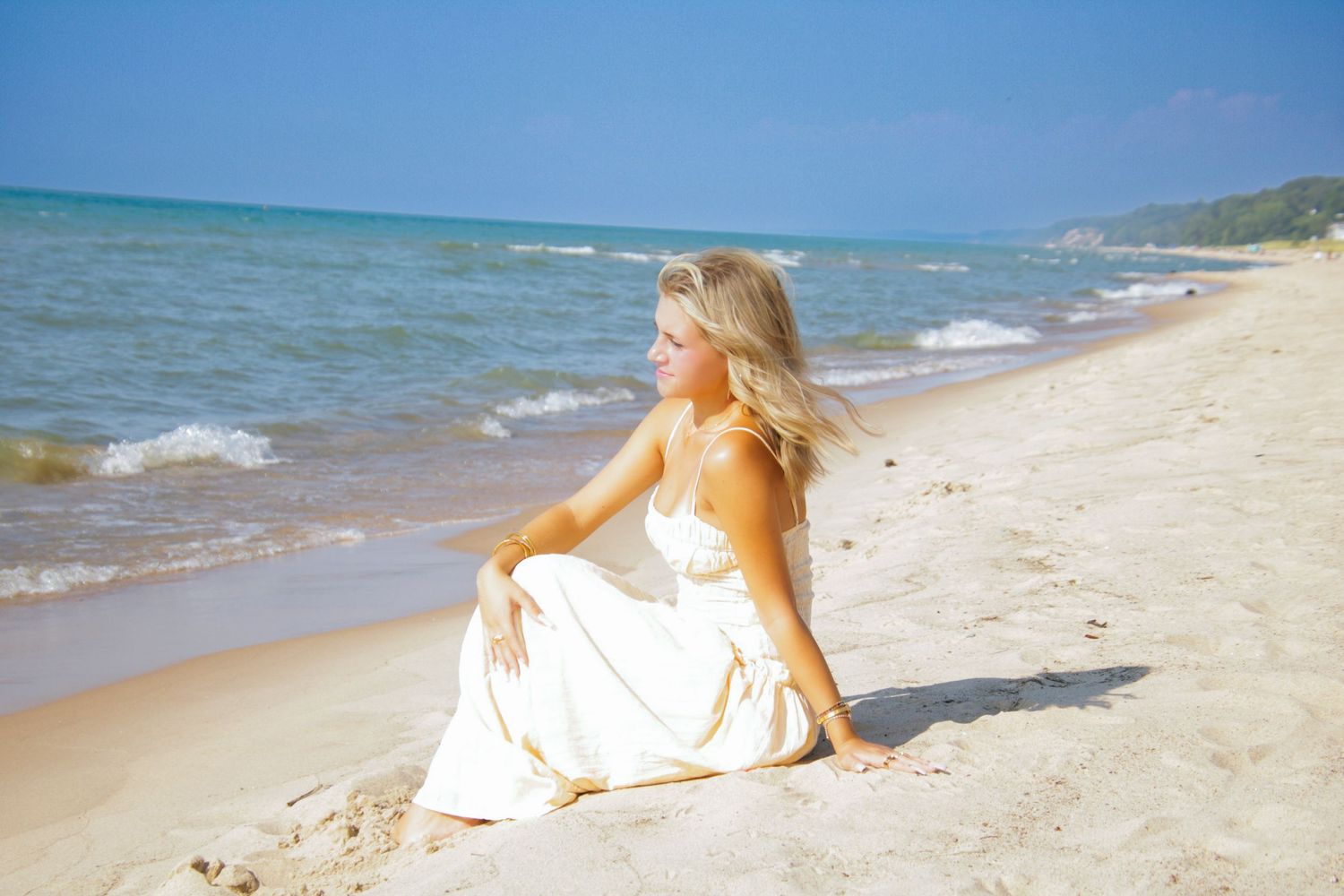 Scenic beach landscape with gentle waves rolling onto pristine sand under blue skies.