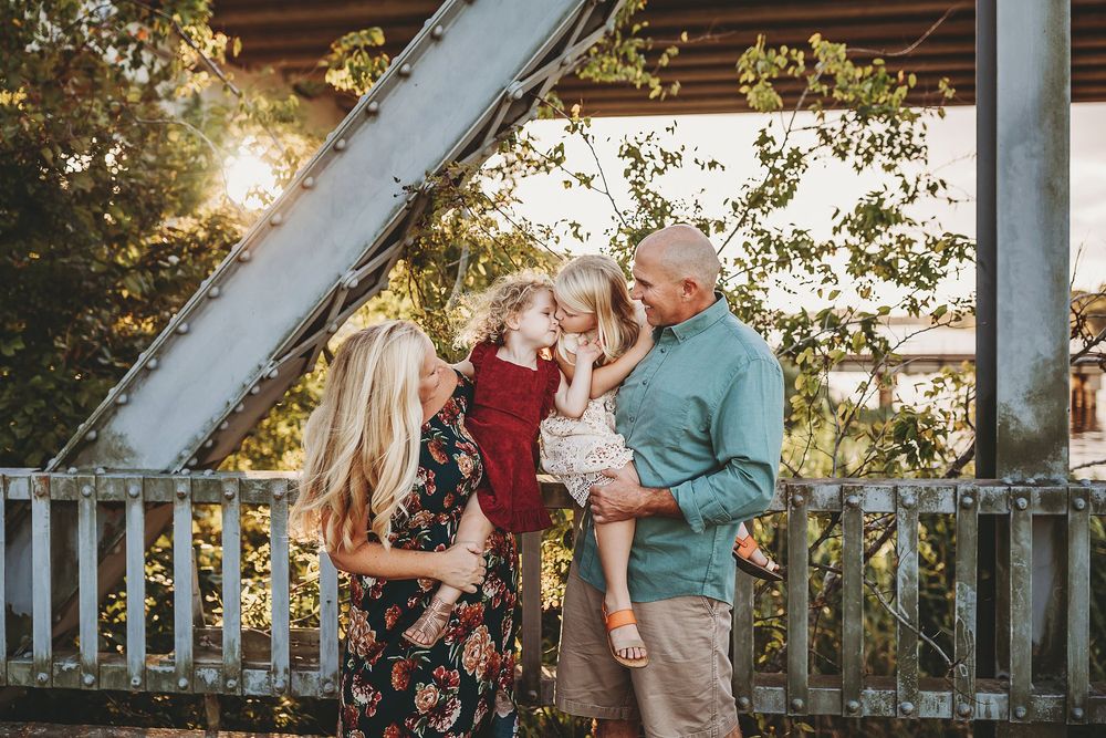 A family gathering outdoors at sunset with wooden beams and golden sunlight filtering through the scene.