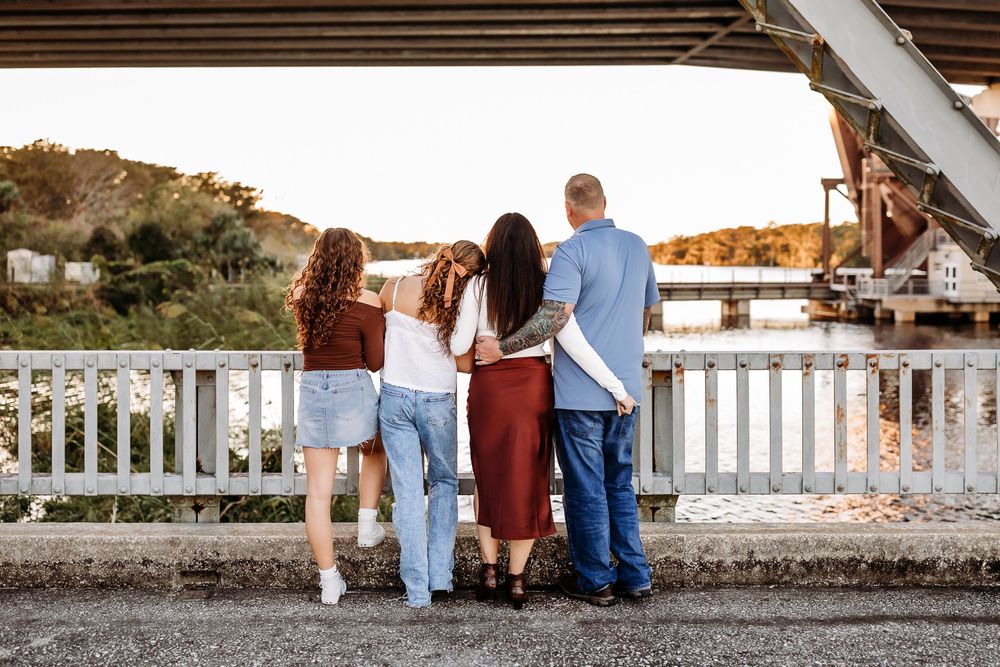 Family walking along a white picket fence at sunset during a photography session at a rustic outdoor location.