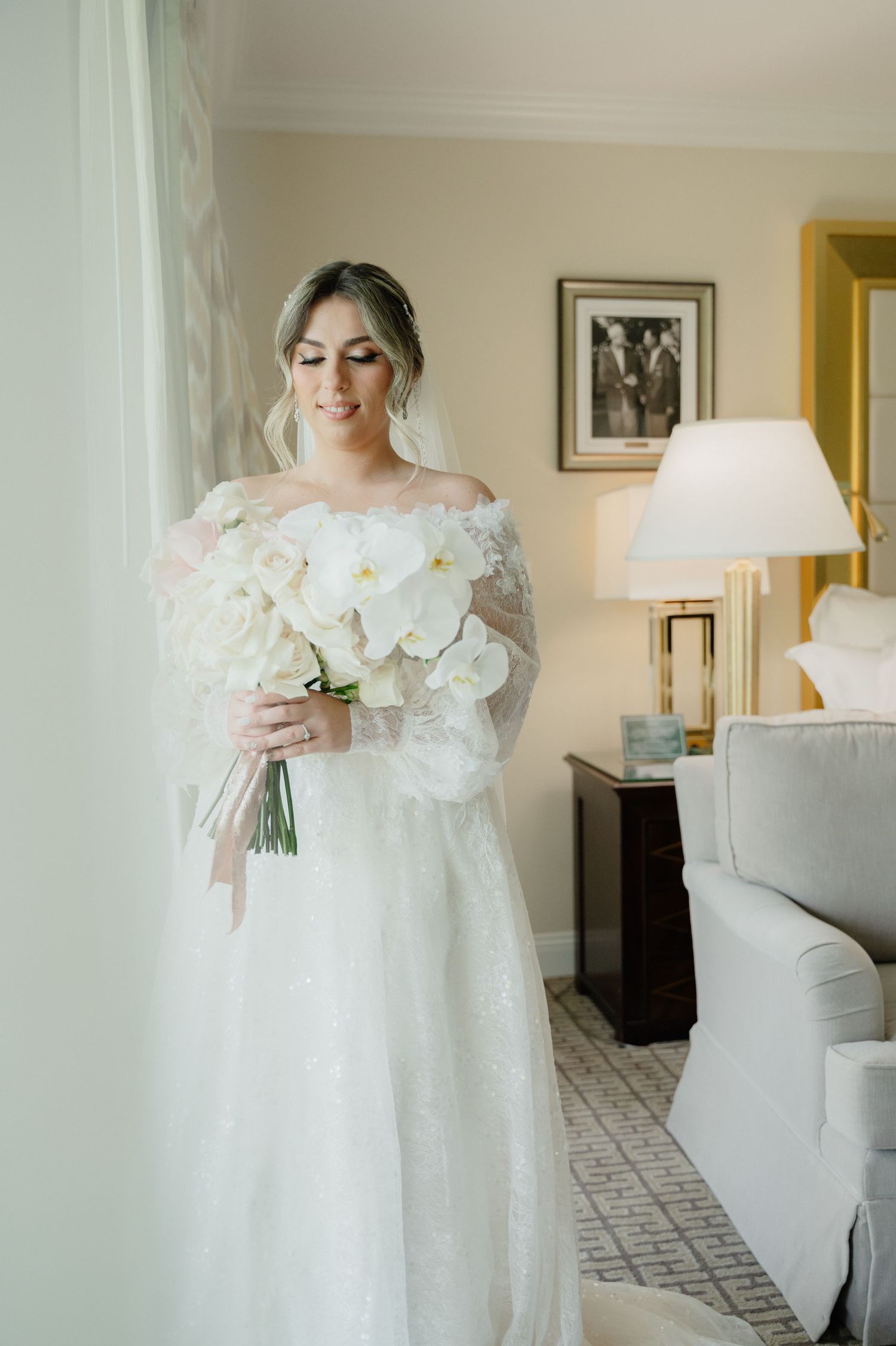 An elegant white orchid bridal bouquet held in a natural-light setting with classic decor.