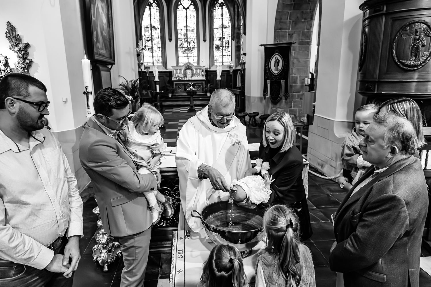 Multiple wedding guests mingle and dance in a candid series of black and white celebration photos in a church setting.