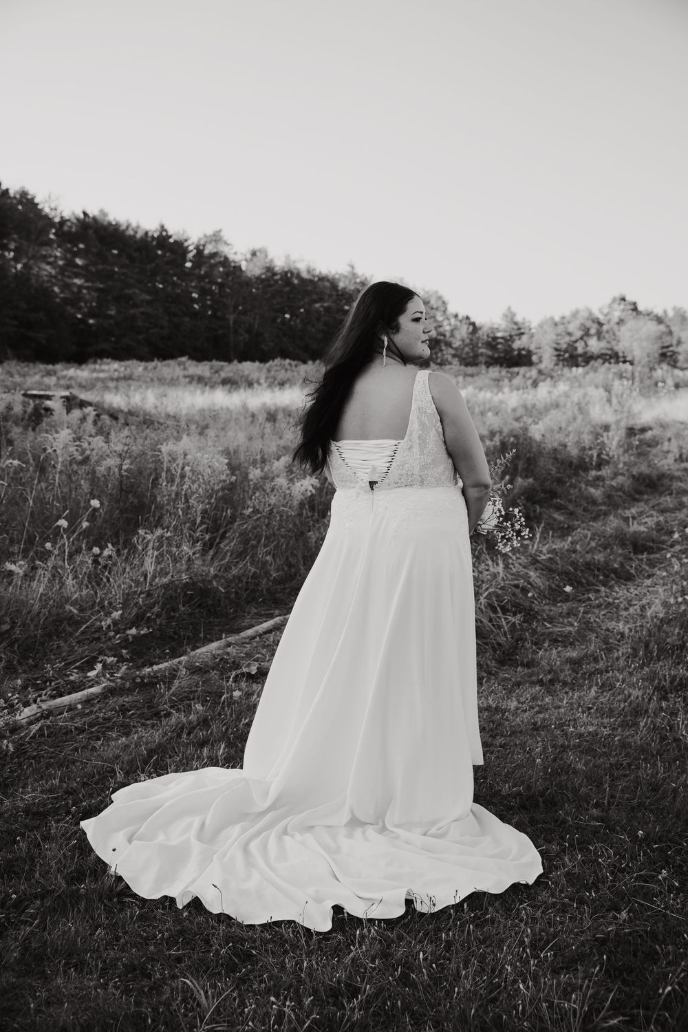A flowing white wedding dress is captured in black and white across a series of artistic photos in a field.