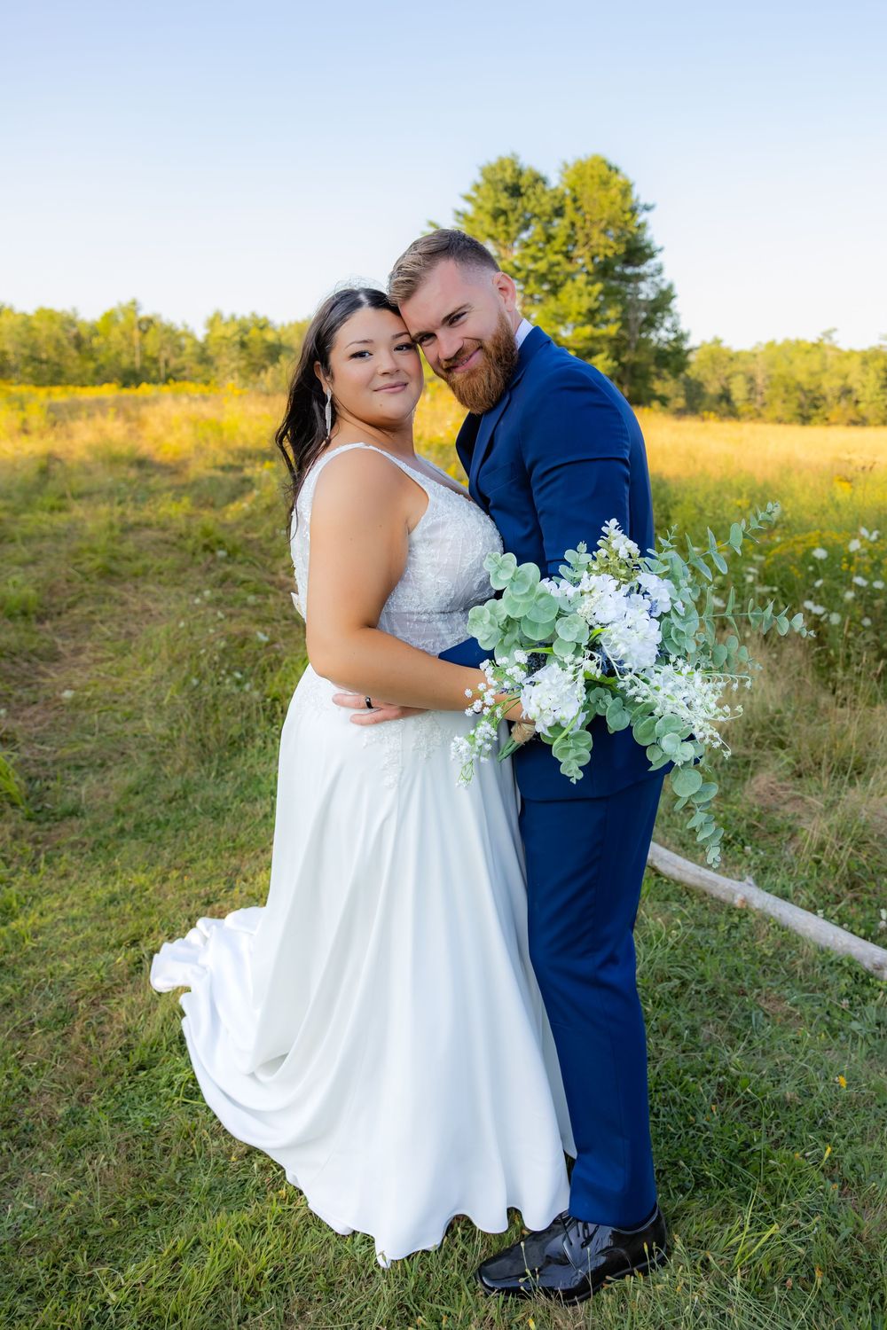 A couple shares intimate moments in a sunny field during their wedding photoshoot.