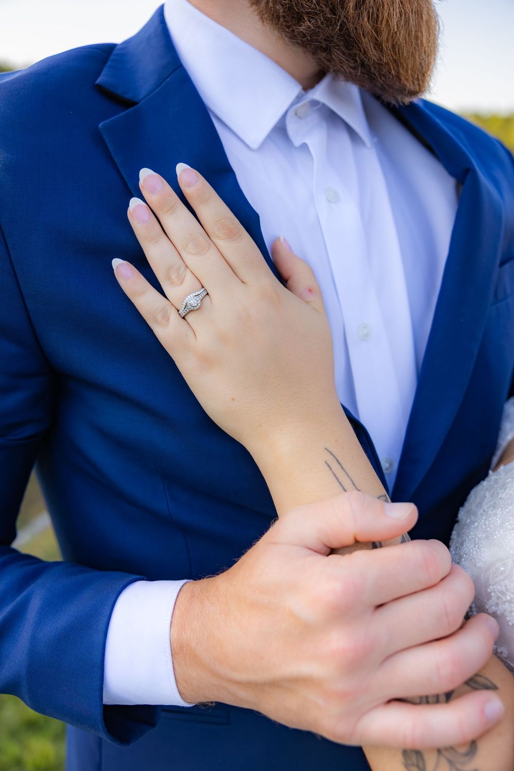 A sequence of engagement photos showing hands embracing with a diamond ring on display against a blue suit backdrop.