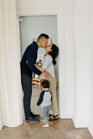 A couple in navy and gray outfits sharing a romantic dance dip pose against a white wall.