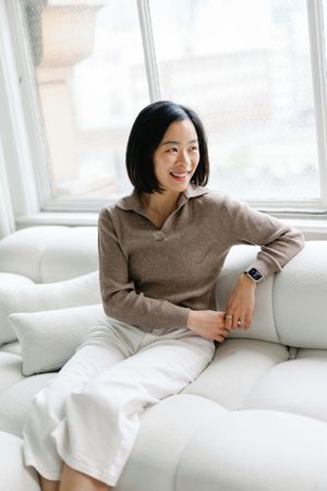 A series of four photos showing someone relaxing on a white couch in a cozy beige sweater.