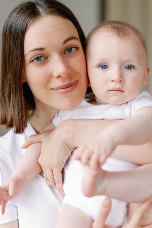 A collage shows close-up portraits of mother and baby in white shirts against light background.