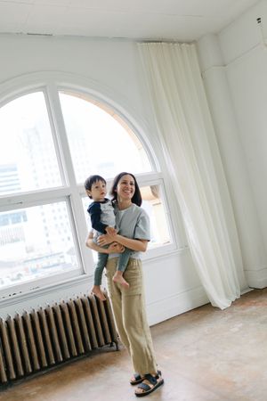 A bright minimalist room with a large arched window, white curtains, and a radiator along the wall.