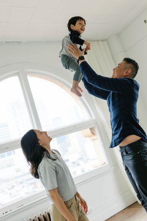 A couple in casual attire dancing together in a bright white room with a large window.