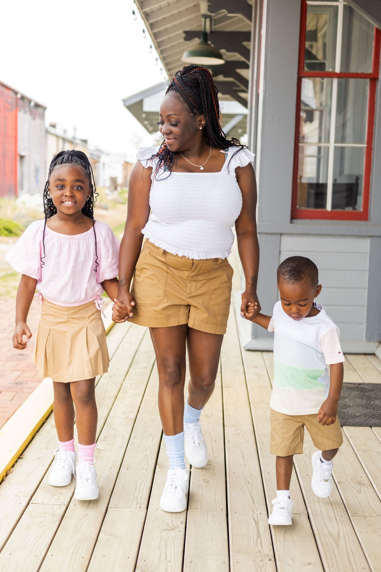 Family wearing coordinated outfits walking together on wooden deck.