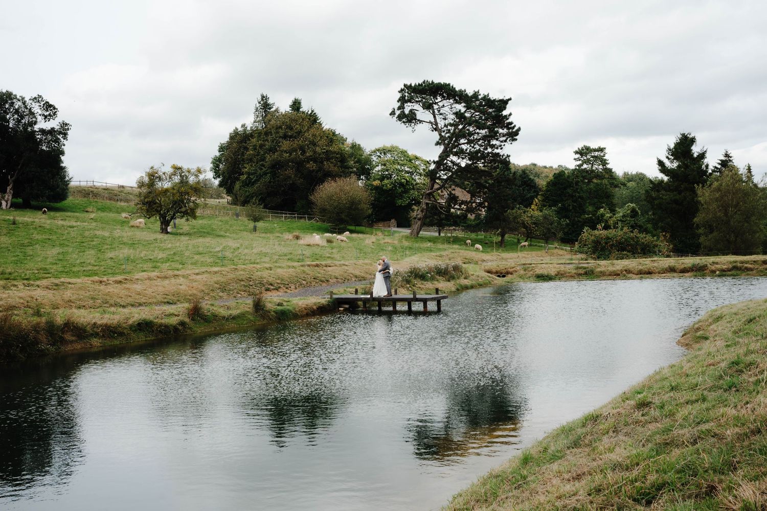 Kingscote Barn Wedding Photographer Zara Davis Photography Cotswolds Gloucestershire Cheltenham bride groom on lake jetty