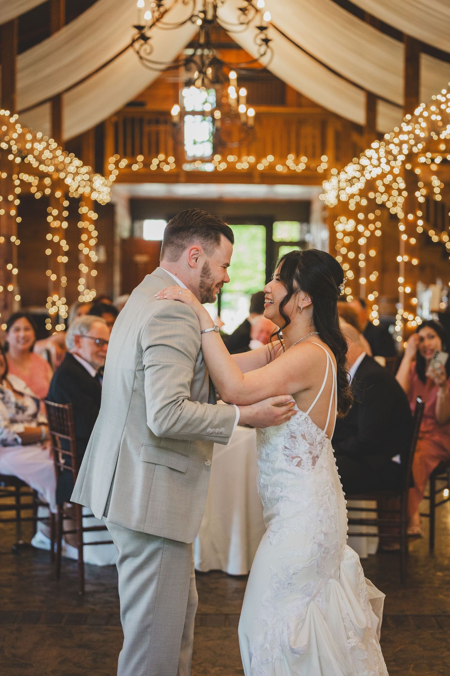 Couple shares romantic first dance under twinkling lights in a rustic barn venue at the stable bluemont vineyard