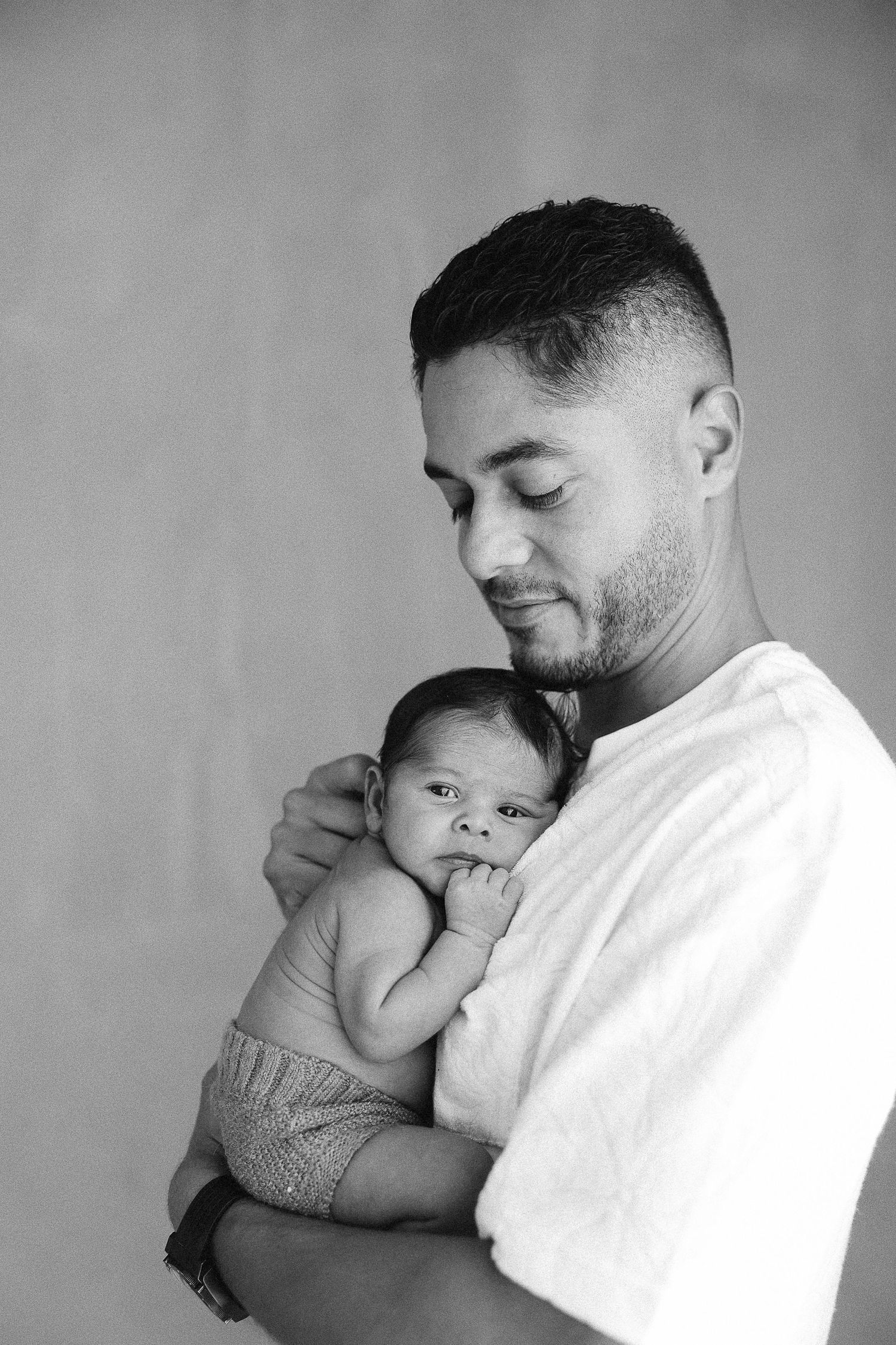 Series of tender black and white photographs showing a father holding and bonding with a small infant in an intimate moment.