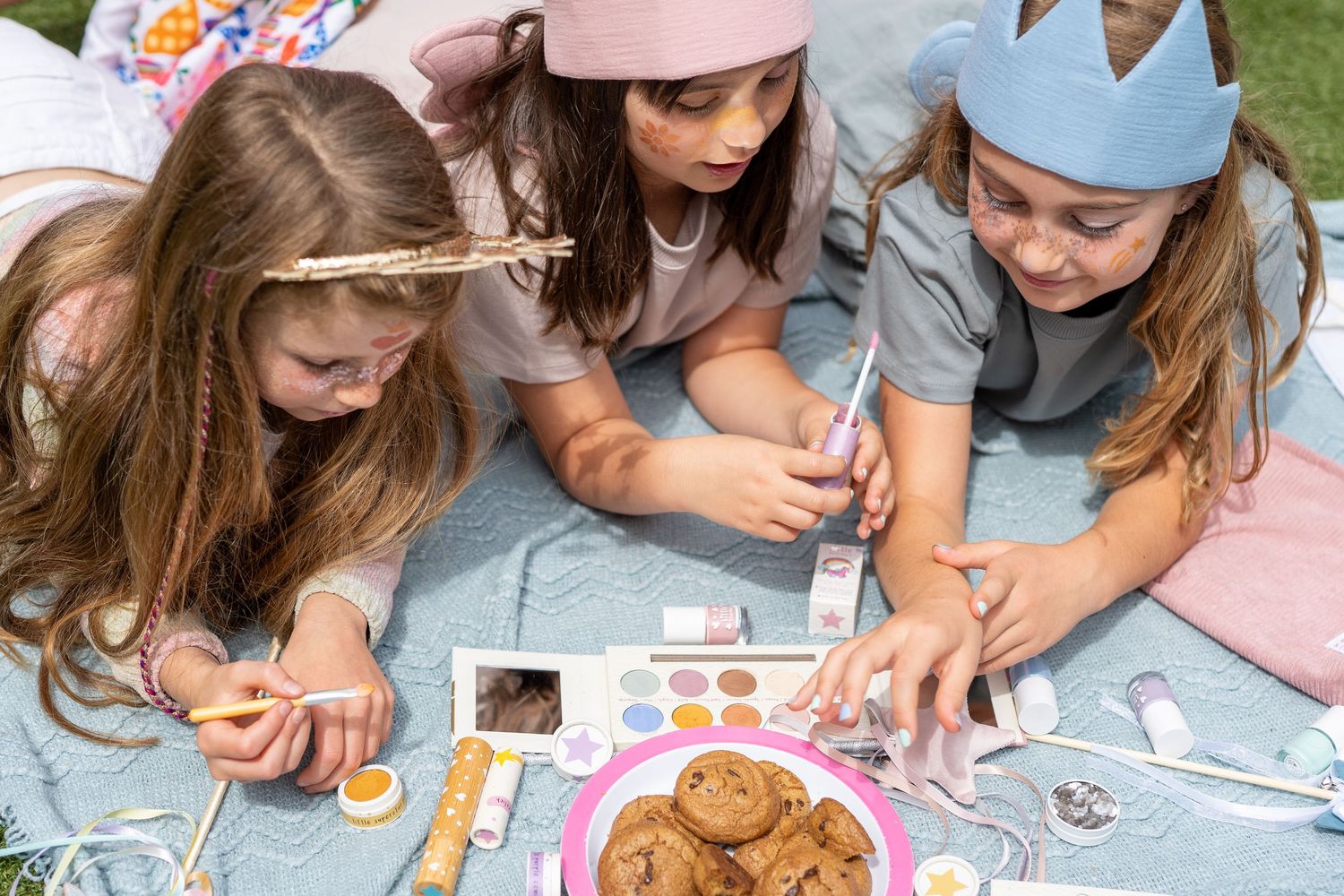 Children gather around a table decorating cupcakes and cookies with frosting and sprinkles during a crafting activity.