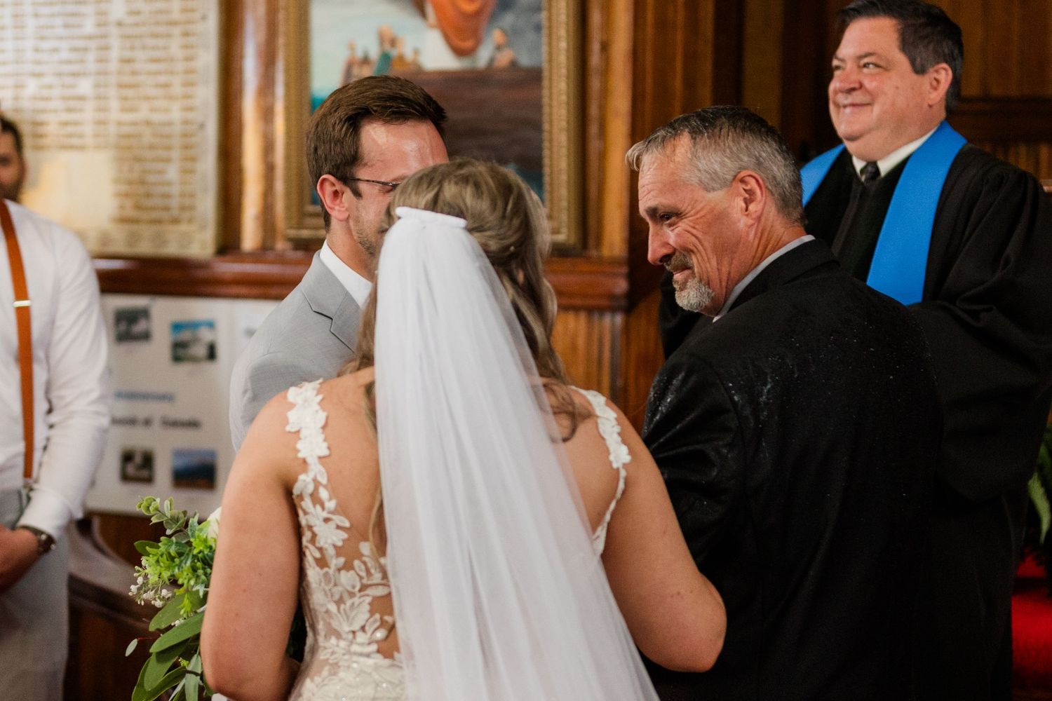 Joyful wedding ceremony moment inside wooden-paneled church with emotional couple and guests looking on.
