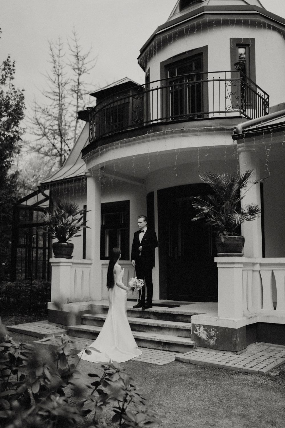 Black and white photo of an elegant white house with curved balconies and columns.