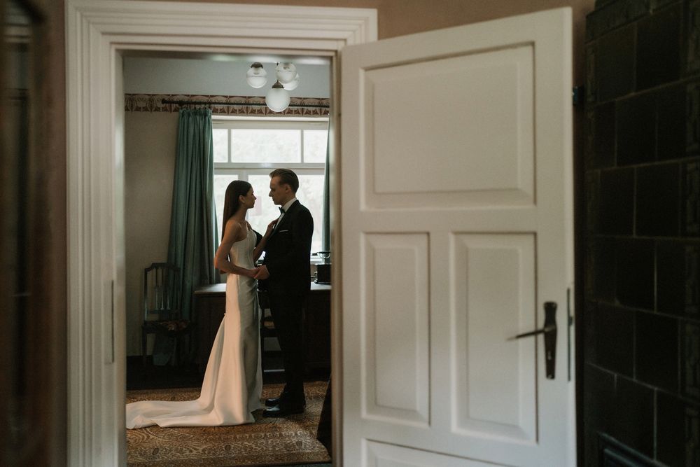 Elegant white doorways frame a romantic wedding scene with natural window light.