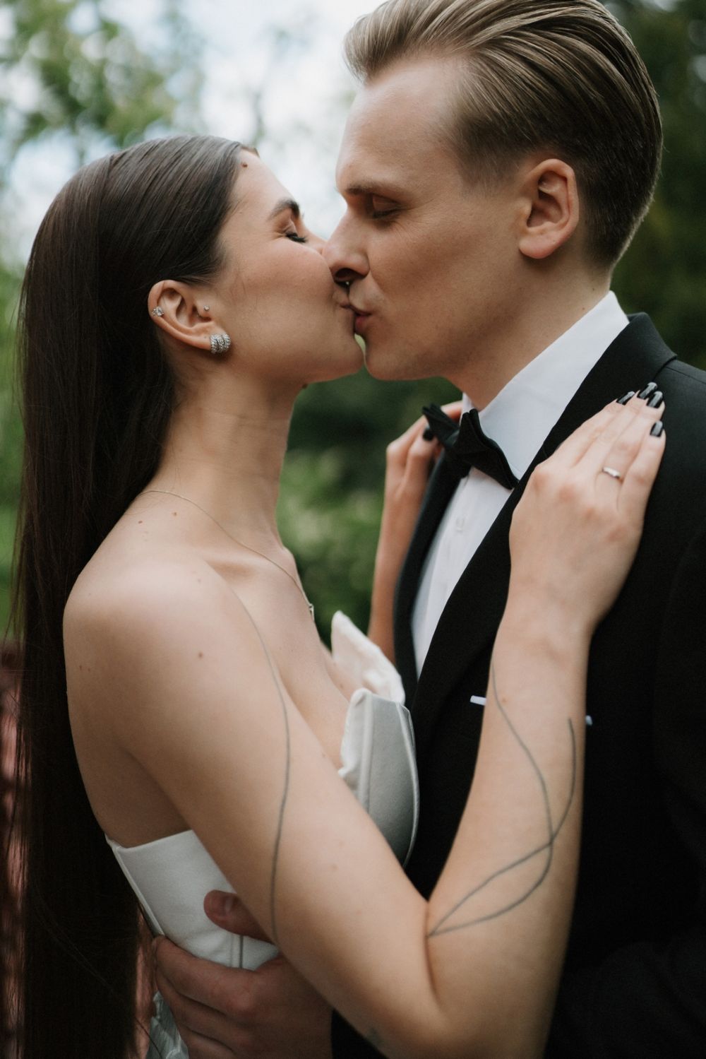 Outdoor wedding portrait showing tender embrace against natural greenery background.