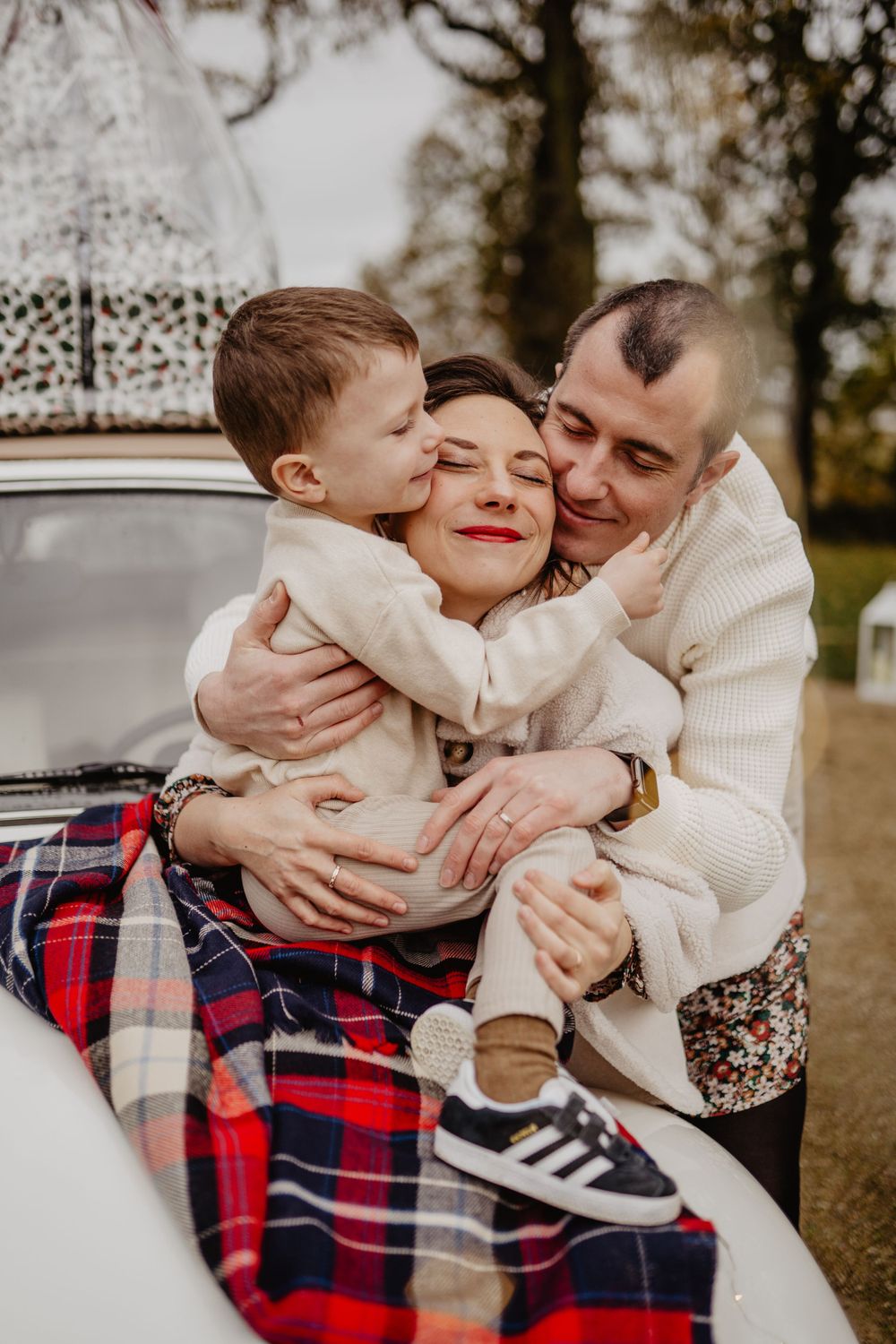 Moment familial confortable sur une couverture avec camping-car blanc en arrière-plan pendant la séance photo en plein air noël
