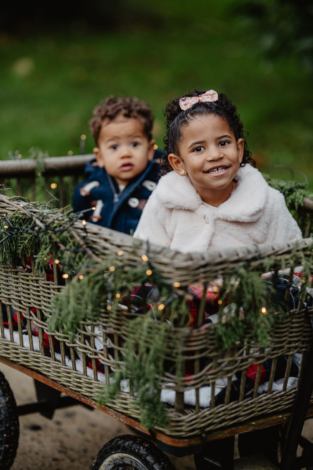 Deux jeunes enfants sont assis ensemble dans un chariot rustique en osier décoré de verdure et d'ornements de Noël
.chateau de beaussais