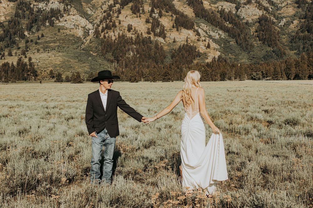 A romantic wedding photoshoot in a scenic mountain meadow with golden natural lighting.