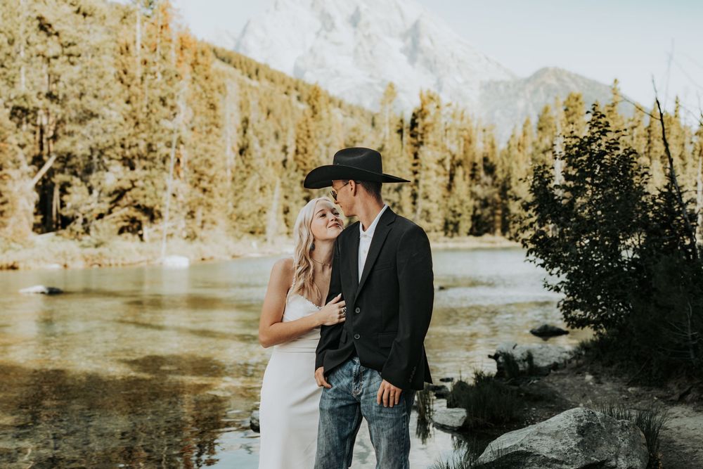 Couple shares an intimate moment by a scenic mountain lake surrounded by golden autumn foliage.