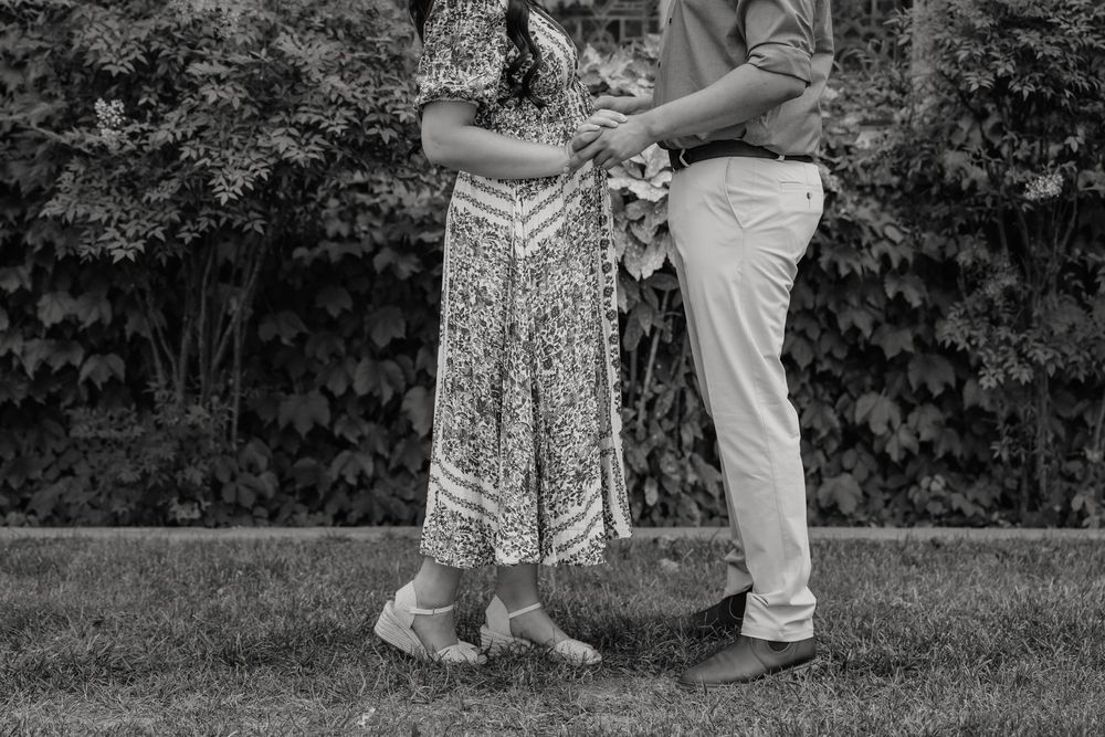 A couple dancing and embracing outdoors in a garden with greenery and trees in the background.