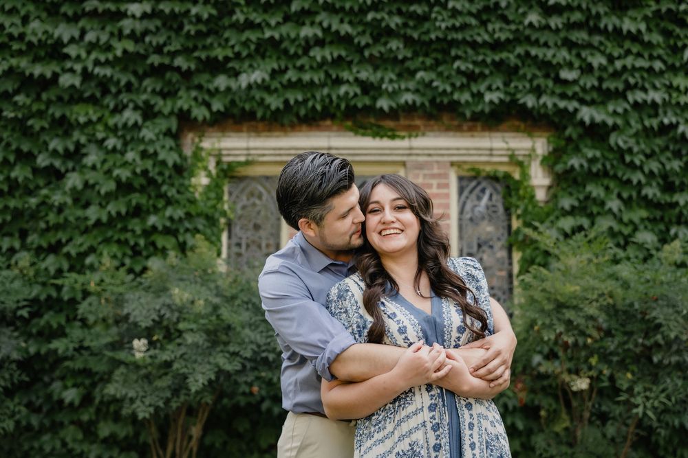 A romantic embrace near an ivy-covered wall in a garden setting.