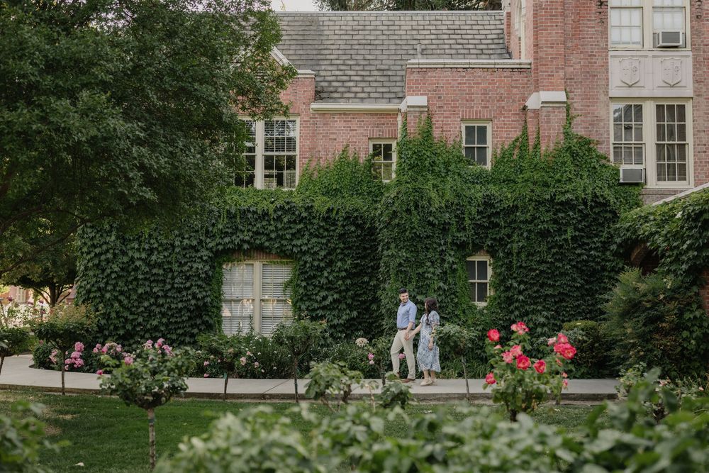 A romantic moment in a lush garden courtyard with ivy-covered brick walls and blooming roses at dusk.