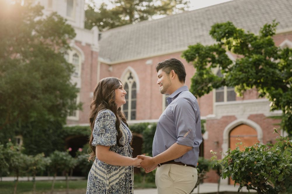 A couple shares an intimate moment together outside a brick church with stained glass windows during golden hour.