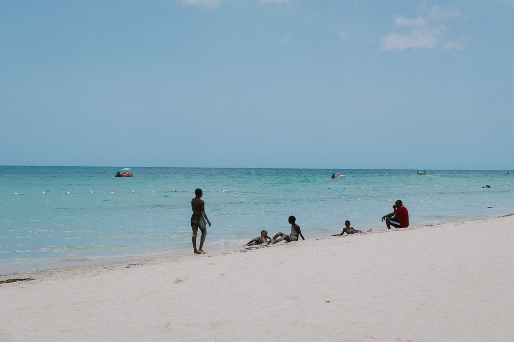 People enjoy a sunny day on a pristine white sand beach with turquoise waters in the Caribbean.