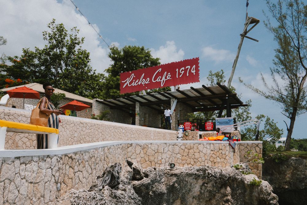 Stone steps lead up a rocky hillside with red signs and cafe awnings visible at the top of the outdoor staircase.