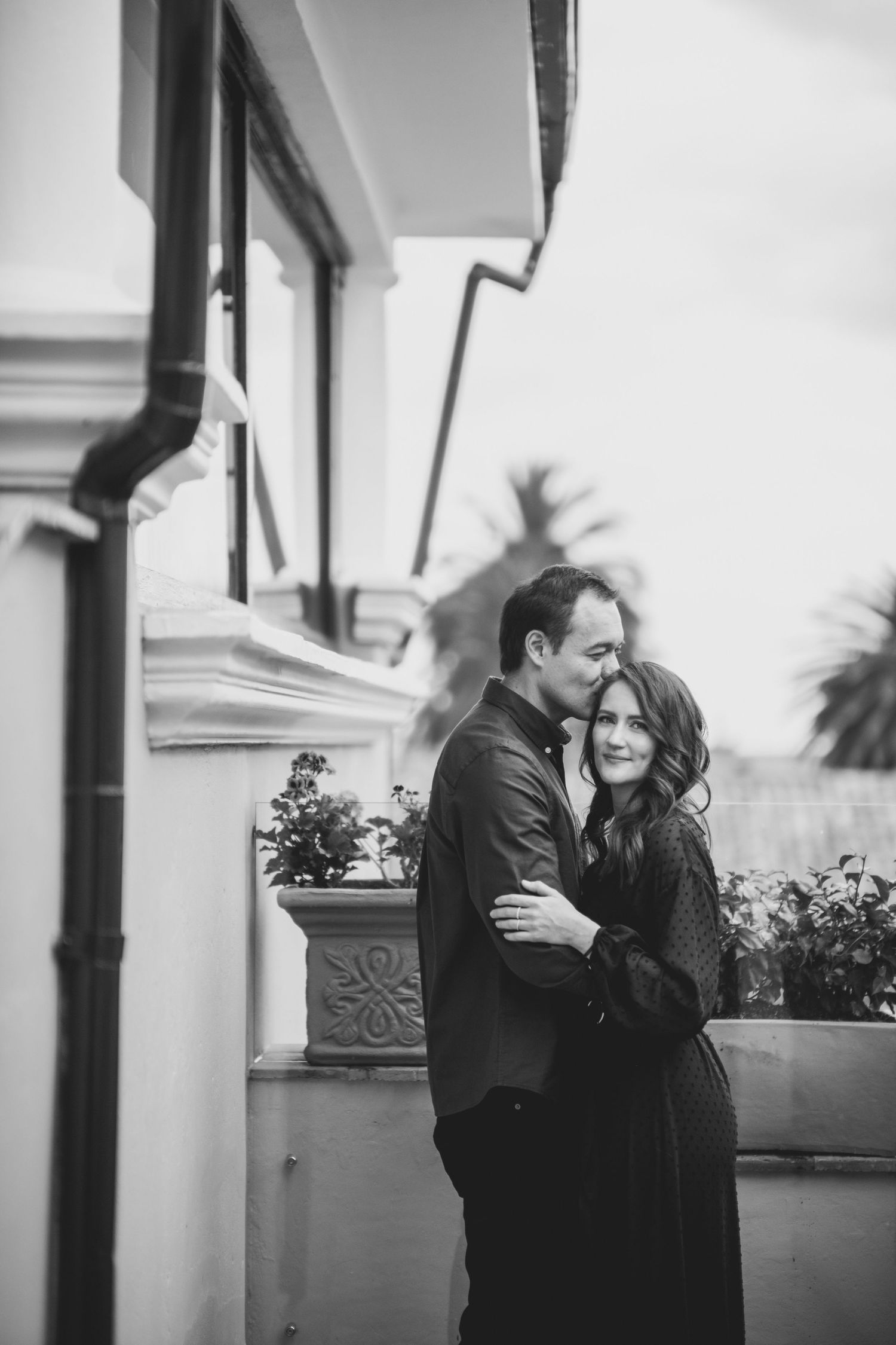 A black and white sequence of four intimate romantic moments showing a couple embracing and laughing together.